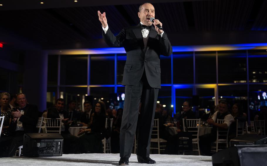 Singer Lee Greenwood in a suit on stage, singing “God Bless the USA,” on Nov. 22, 2024.