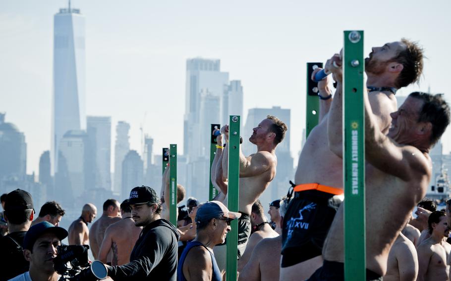 Participants completing pull-ups during the Navy SEAL swim, with the World Trade Center seen in the background. 