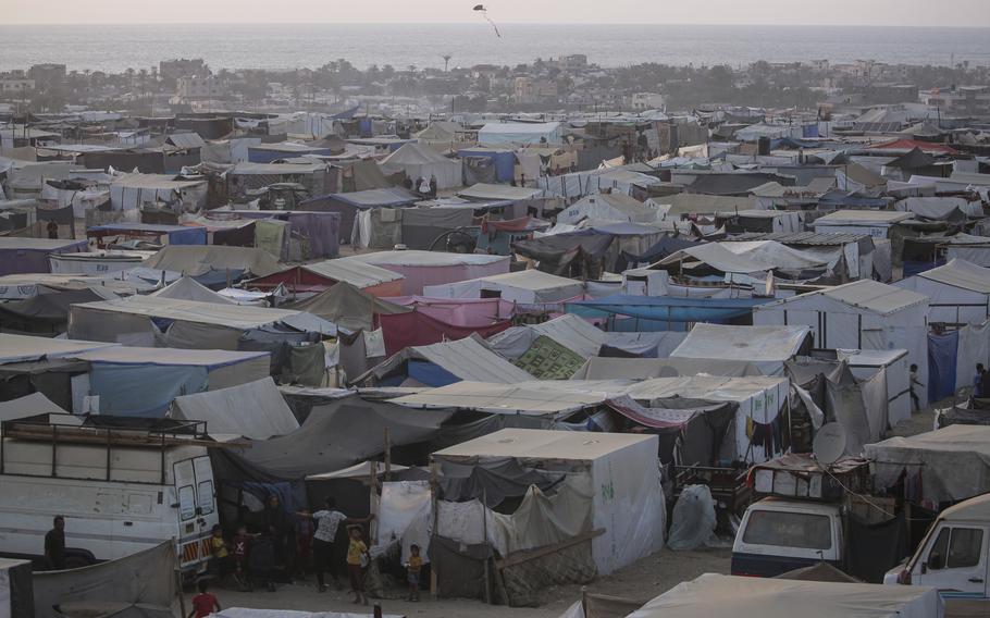 Palestinians displaced by the Israeli air and ground offensive on the Gaza Strip walk through a makeshift tent camp in Khan Younis, Gaza, on June 18, 2024. 