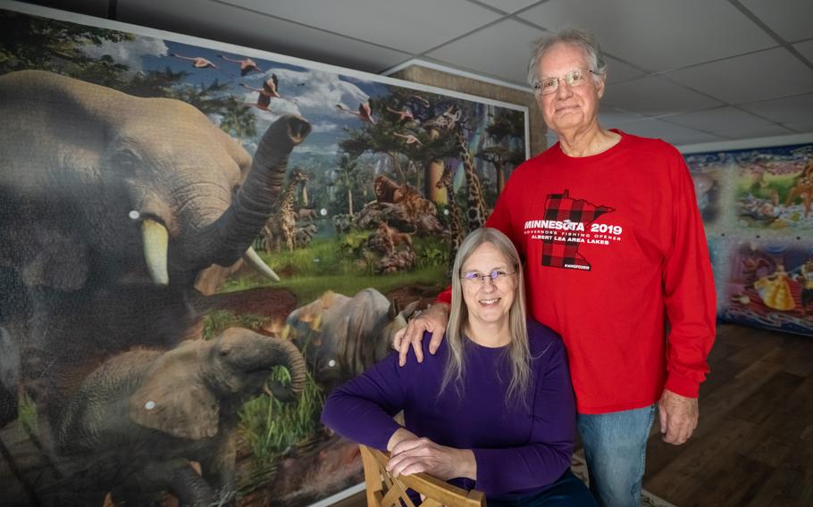 Avid puzzler and puzzle collector Linda Groskreutz, 67, poses for a portrait with her husband Jeff, 69, in front of two giant puzzles on display in their home in Madison Lake, Minn. 