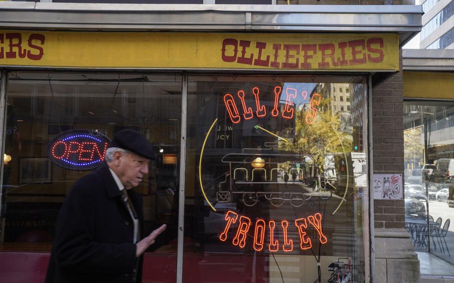 A pedestrian walks past one of the neon signs at Ollie’s Trolley on Nov. 16. The landmark Washington burger joint will soon be shutting down.
