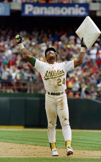 Rickey Henderson raises the base he just stole high into the air.