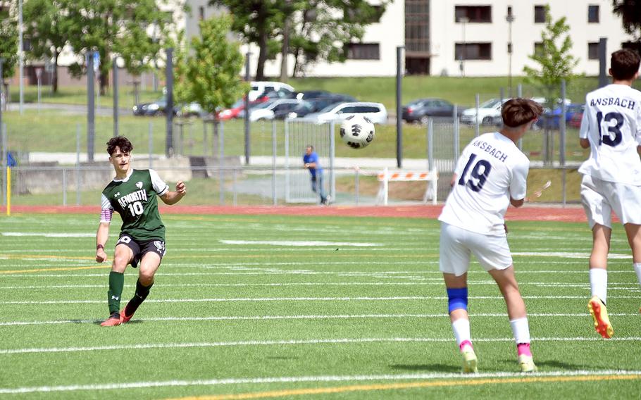 AFNORTH's Christian Barone hits a free kick as Ansbach's Nathan Arrequin and Daymien Abitua jump in the wall during the Division III boys title match at the DODEA European championships on May 23, 2024, at Ramstein High School on Ramstein Air Base, Germany.