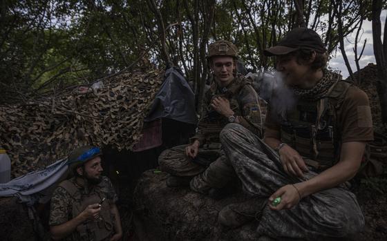 Soldiers with the call sign Witcher, 19, center, Labrador, left, and Miami, right, from Ukraine's 78th Assault Regiment chat about using humor to deal with war after arriving at a trench, forward from the village of Mala Tokmachka before dawn on July 7 in Zaporizhzhia, Ukraine. MUST CREDIT: Photo for The Washington Post by Ed Ram.