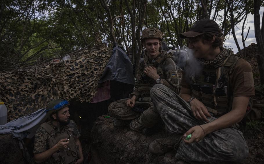 Soldiers with the call sign Witcher, 19, center, Labrador, left, and Miami, right, from Ukraine’s 78th Assault Regiment chat about using humor to deal with war after arriving at a trench, forward from the village of Mala Tokmachka before dawn on July 7 in Zaporizhzhia, Ukraine. 