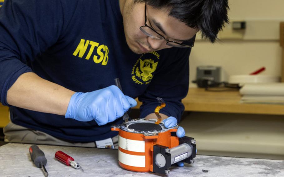 In this image provided by the National Transportation Safety Board, a NTSB investigator examine cockpit voice recorder and flight data recorder in Washington.