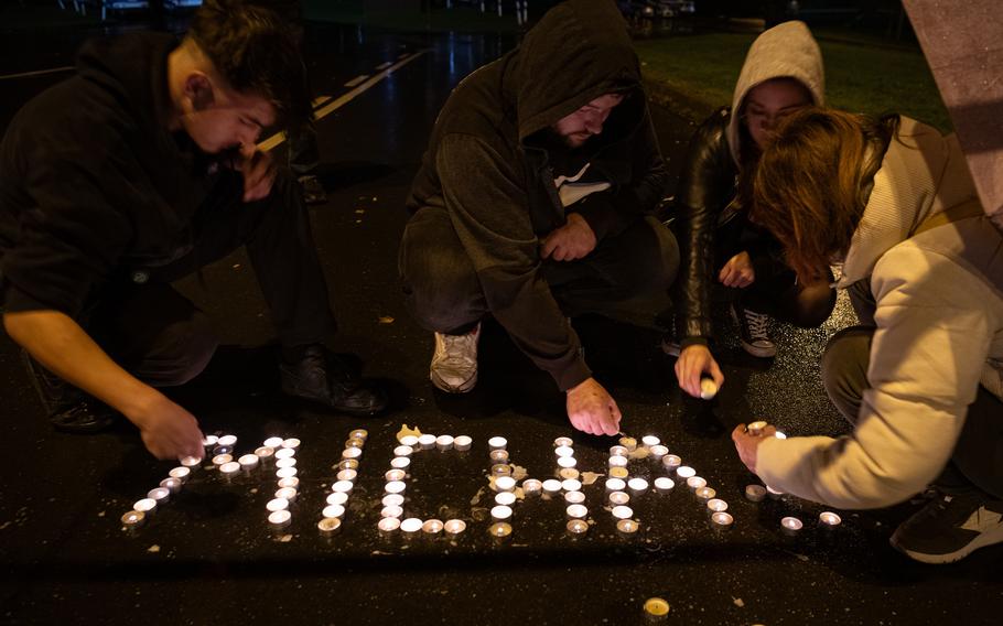 Four protesters put down lit tealights to spell “Micha.” 