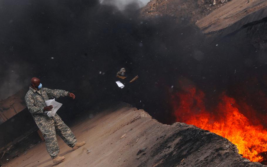 Master Sgt. Darryl Sterling, an equipment manager with the 332nd Expeditionary Logistics Readiness Squadron, tosses unserviceable uniform items into a burn pit at Balad Air Base, Iraq, on March 10, 2008. Inclusion on the Department of Veterans Affairs burn pit registry is now automatic for certain deployment locations, including Iraq.