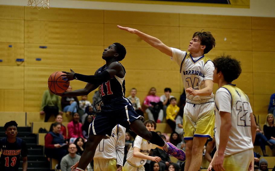 Lakenheath's David Kumi-Baah goes up for a layup while Wiesbaden's Hayden Tallant defends from behind during a Dec. 1, 2023, game at Wiesbaden High School in Wiesbaden, Germany.