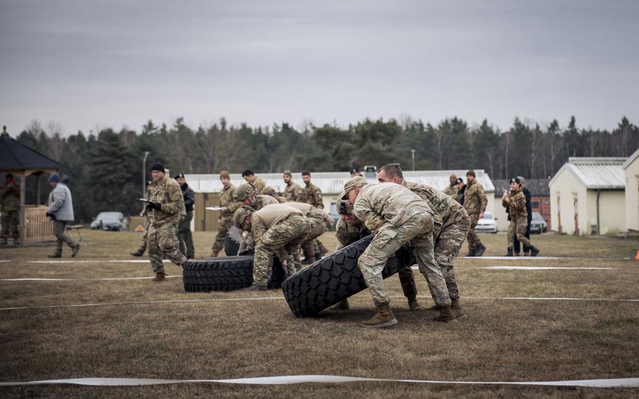 Service members try to flip giant tires during a competition.  