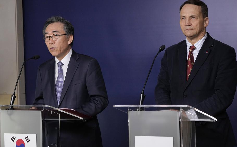 Two men in suits stand at podiums emblazoned with their respective flags.