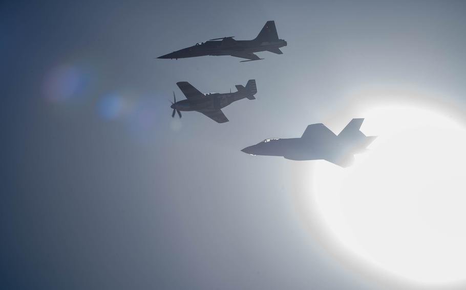 Three aircraft fly in formation through the glare of the sun.