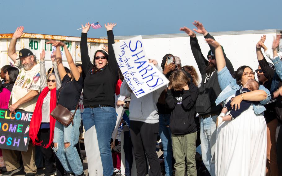 Family and loved ones hold signs during a homecoming ceremony for the USS Stockdale