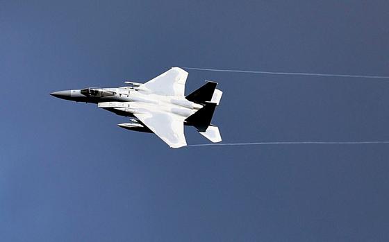 A fighter jet streaks across a blue sky.