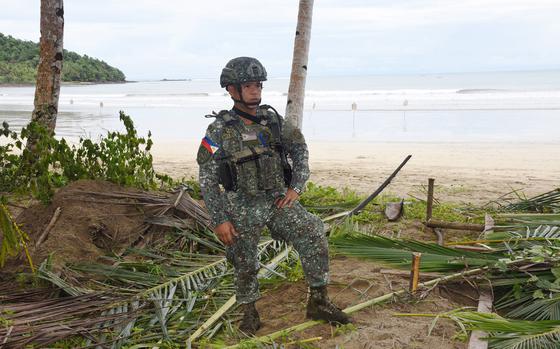 A man in uniform stands in front of the beach.