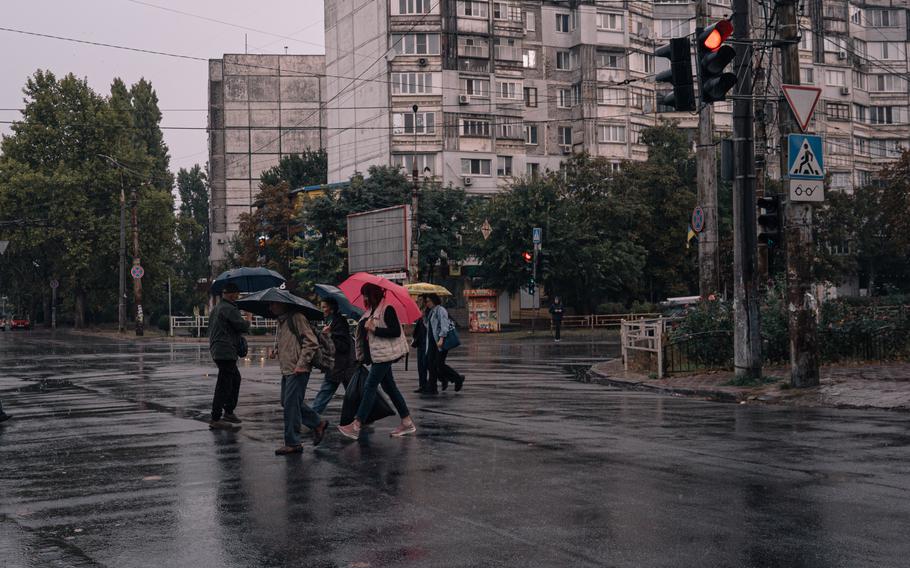 A group of pedestrians with umbrellas walking during a rainy day in Kherson.