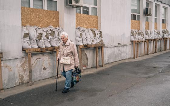 A woman passes by a hospital in Kherson that has its windows covered with wooden planks and sandbags.