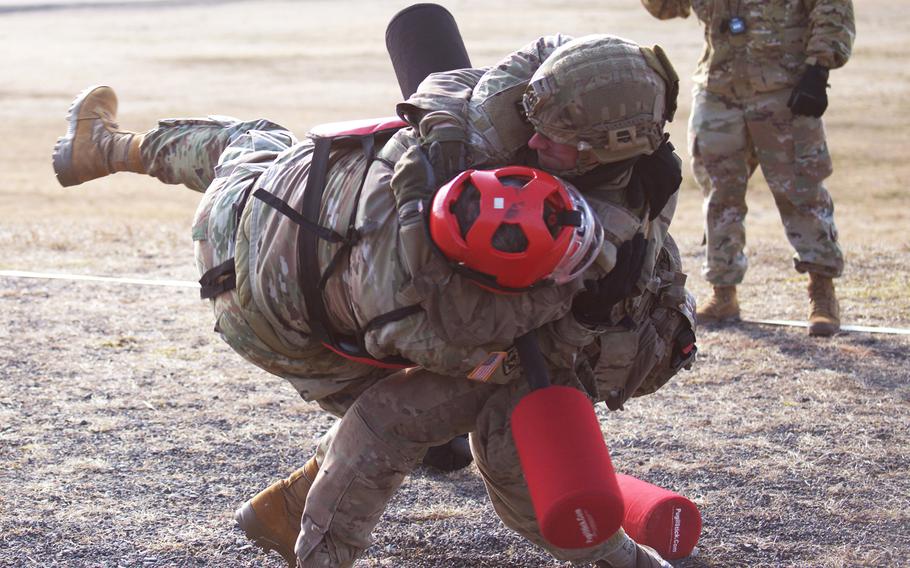 A Danish service member tosses a U.S. sergeant wearing a red safety helmet onto the ground.