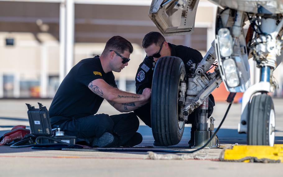 Two crew members work on a tire.