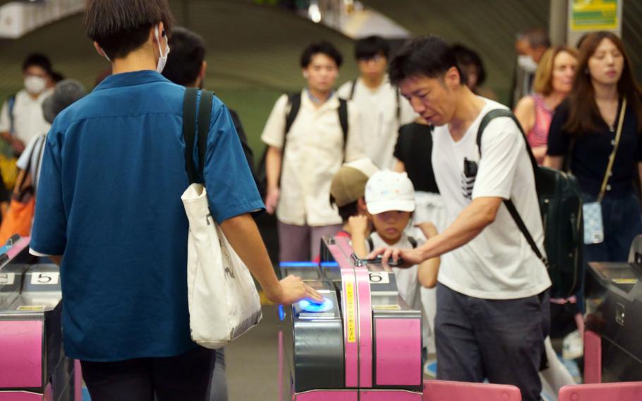 Commuters pass through a ticket gate at Shibuya Station in Tokyo, Aug. 23, 2023. 