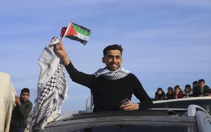 Displaced Palestinians wave the Palestinian flag as they return to Rafah, while a ceasefire deal between Israel and Hamas went into effect, in Rafah, Gaza Strip, Sunday, Jan. 19, 2025. (AP Photo/Mariam Dagga)