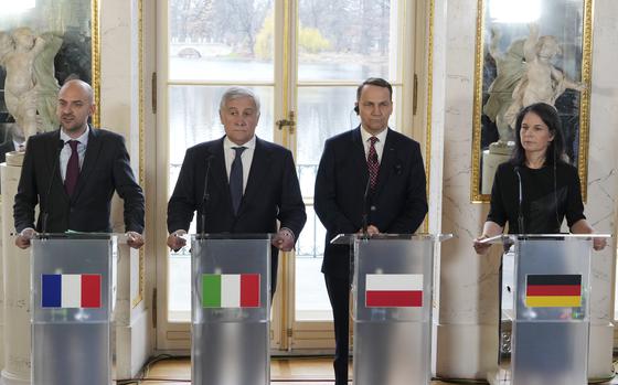 Four government officials stand at podiums with the flags of their countries on them at a press conference.