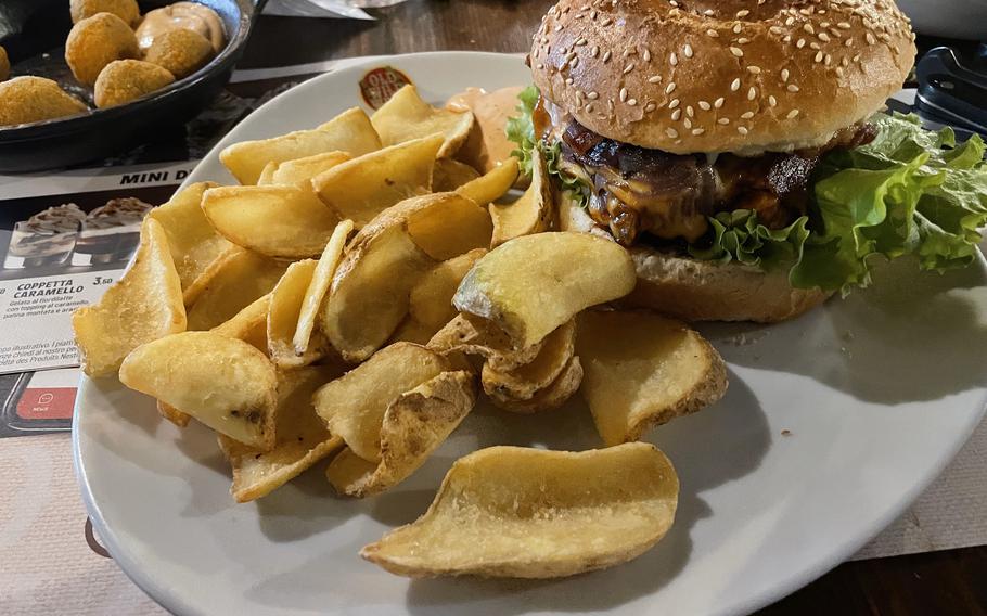 The pulled chicken sandwich served with fried potato slices from Old Wild West in Fiume Veneto, Pordenone, Italy on May 14th, 2024. In the upper corner are the fried green olives, known as "green balls" on the menu. 