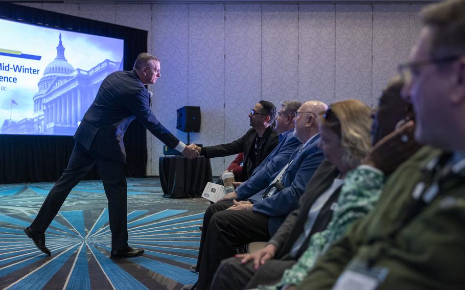 Collins standing and shaking the hand of a seated veteran.