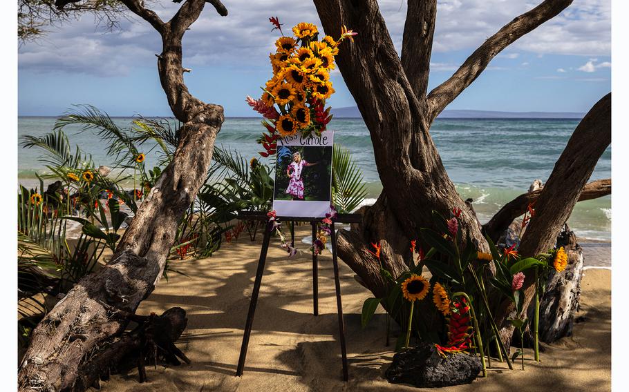 A tribute to Carole Hartley, who died in the Aug. 8 fires in Lahaina, stands at Ukumehame Beach near Lahaina, Hawaii, during a celebration of her life on Monday, what would have been her 61st birthday. 