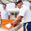 A soldier in dress uniform and white gloves places a wooden case into a casket, while another soldier in dress uniform stands at attention next to the casket.