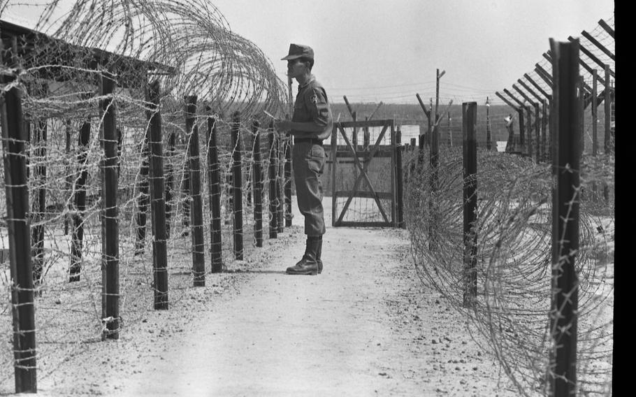 A Vietnamese guard stands between two barbed wire fences at the Bien Hoa POW camp.