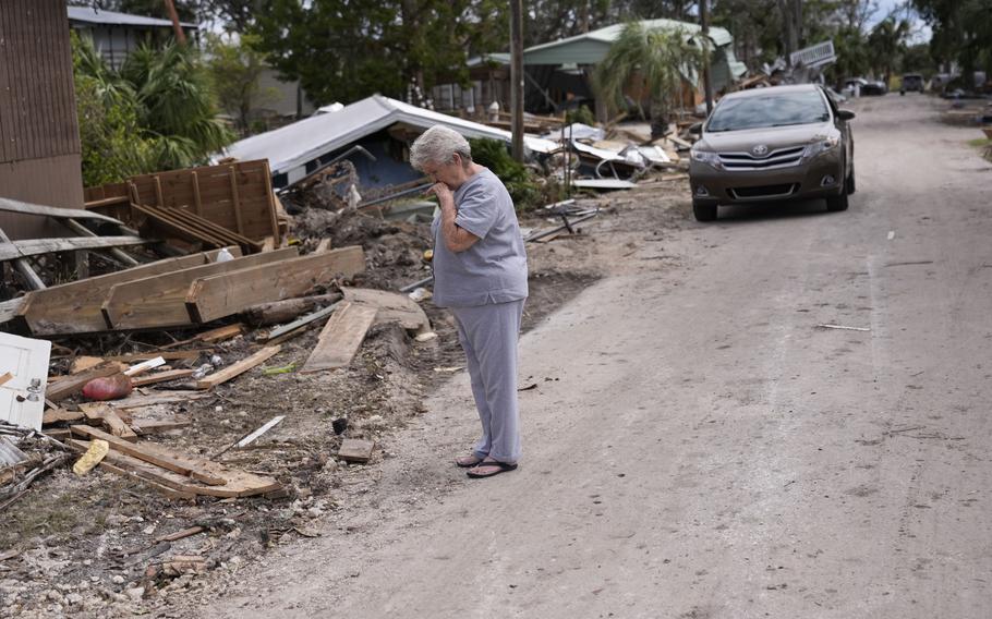 Elise Hicks stands in front of her home in Horsehoe Beach, Fla., assessing the damage after Hurricane Helene swept through.