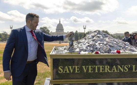 In this photo provided by the Heroic Hearts Project, Jesse Gould adds 22 dog tags signifying the number of veterans estimated to die by suicide in one day, at a memorial paying tribute to the estimated 150,000 veterans who have lost their lives to suicide over the past 20 years, displayed near the U.S. Capitol in Washington on July 10, 2024. (Michael Schoen/Heroic Hearts Project via AP)