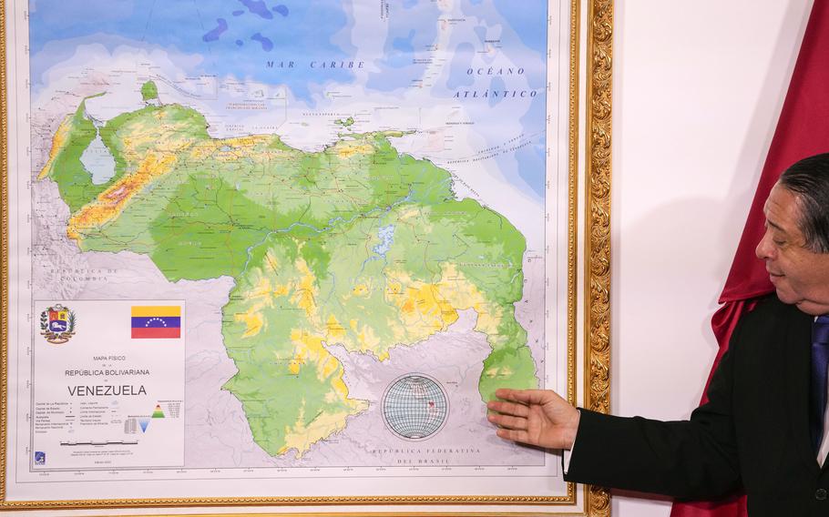 Chairman of the Special Commission for the Defense of Guyana Essequibo Hermann Escarra, stands next to Venezuela’s new map that includes the Essequibo territory, a swath of land that is administered and controlled by Guyana but claimed by Venezuela, during an unveiling ceremony in Caracas, Venezuela, Dec. 8, 2023.