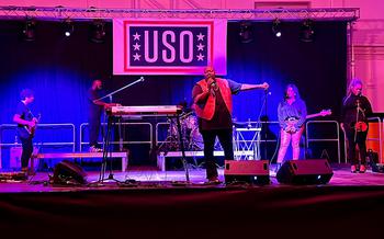 A band performs onstage in front of a USO banner.