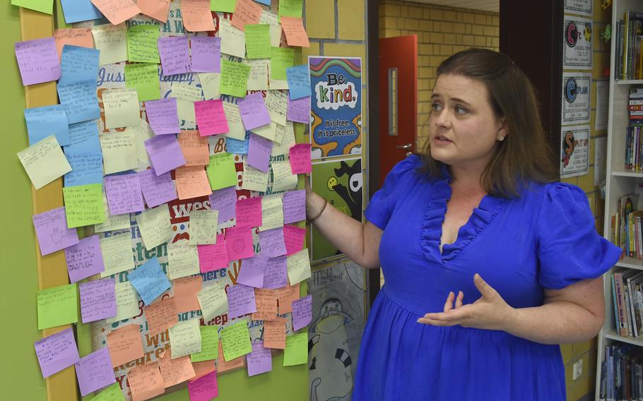 Susan Harris-Boring stands next to a wall covered with sticky notes written by her students