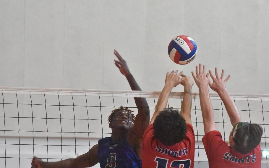 Rota’s Brian Leiba watches the ball bounces off the Aviano block of Kaleb Nunez and Trevor Drummond in the Saints’ four-set victory Saturday, Oct. 14, 2023.