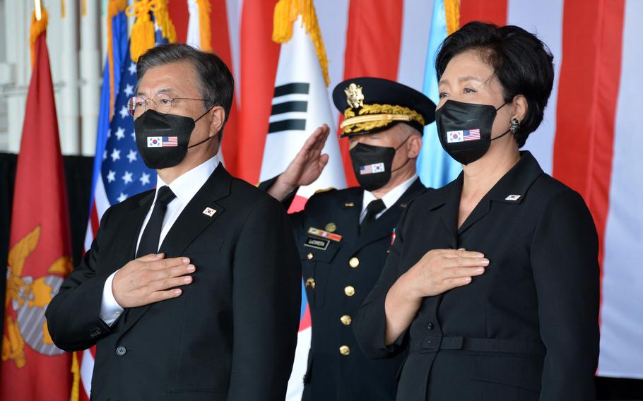 South Korea President Moon Jae-in and his wife, Kim Jung-sook, stand during a remains repatriation ceremony at Joint Base Pearl Harbor-Hickam, Hawaii, Wednesday, Sept. 22, 2021. The commander of U.S. Forces Korea and United Nations Command, Gen. Paul LaCamera, salutes behind them.