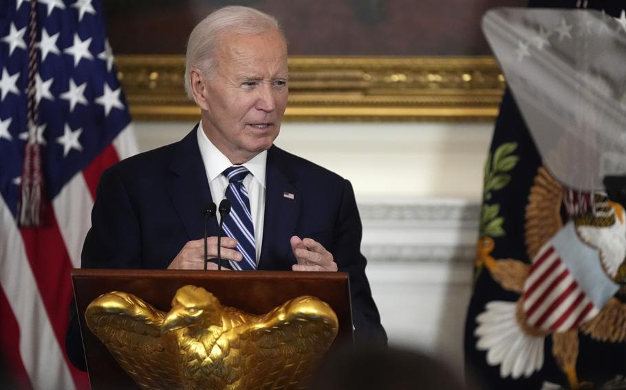 President Biden speaking at a podium with his hands raised slightly.