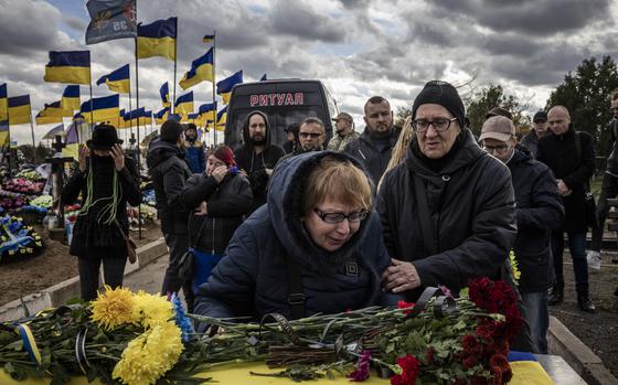 Women mourn a fallen Ukrainian soldier at a cemetery on the outskirts of Kherson last year. MUST CREDIT: Ed Ram for The Washington Post