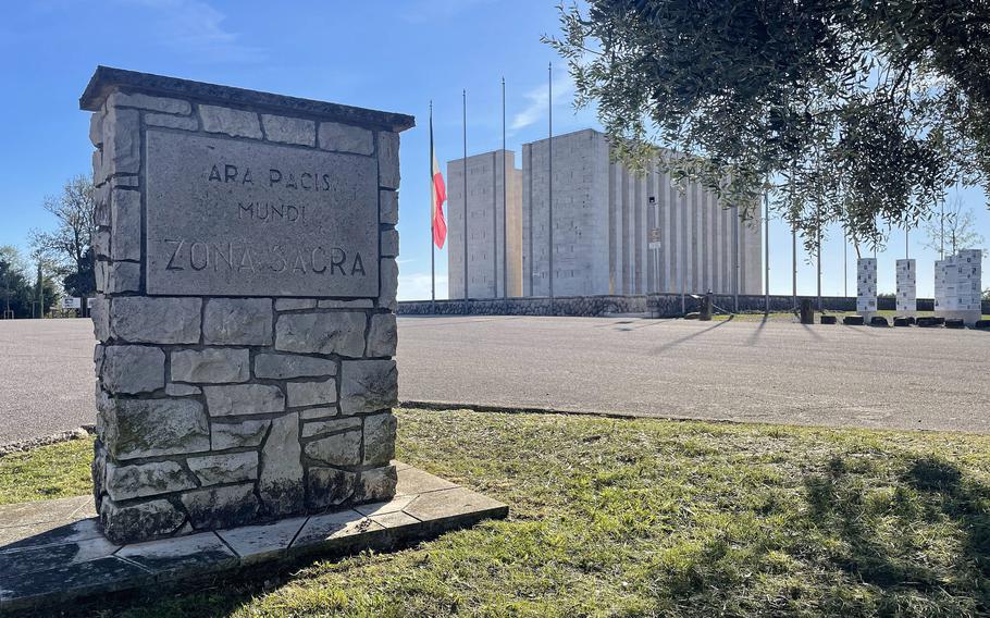 A sign says Ara Pacis Mundi with the monument in the background.