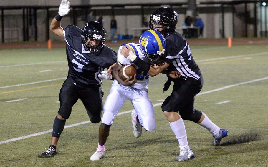 Yokota's Kyshon Banks gets corraled by Zama's Chayden Williams and Greg Horton.