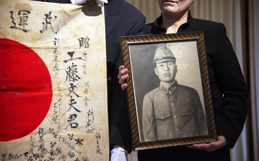 Toshimi Kudo holds a portrait of Fumio Kudo during a ceremony.