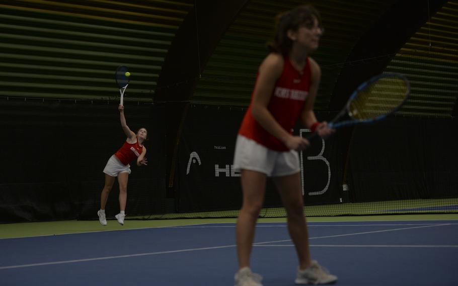 Kaiserslautern's Abby Hover launches into a serve at the baseline while teammate Alisa Dietzel readies herself for the next move during their doubles match against Vicenza's Annika Svenson and Addie Wilson, at the DODEA European tennis championships at T2 Sports Health Club in Wiesbaden, Germany, on Oct. 21, 2023. Kaiserslautern bested Vicenza for the first place in the girls double tournament.