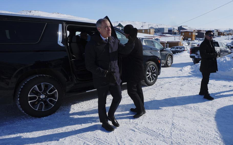 Mark Carney walking out from his black van into a snowy town.