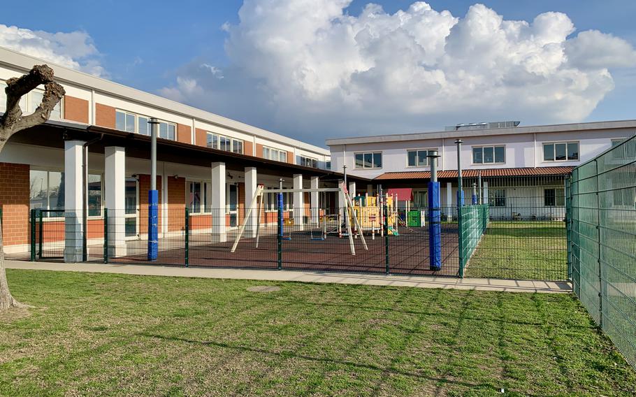 Grass with a playground and school building.