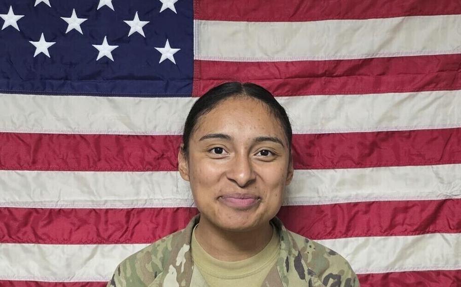 Pfc. Katia Duenas Aguilar poses for a photo in uniform in front of the American flag.