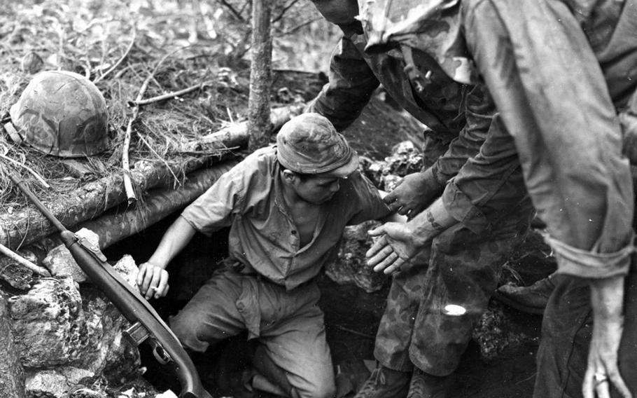 U.S. Marines coax a Japanese sailor into surrendering on Guam, July 1944. 