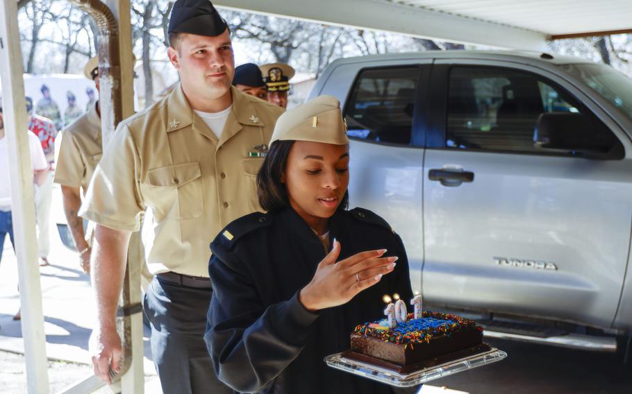 Navy ENS Raven Battles shields the birthday candles of Navy World War II veteran Elsie Kitty Rippin’s cake