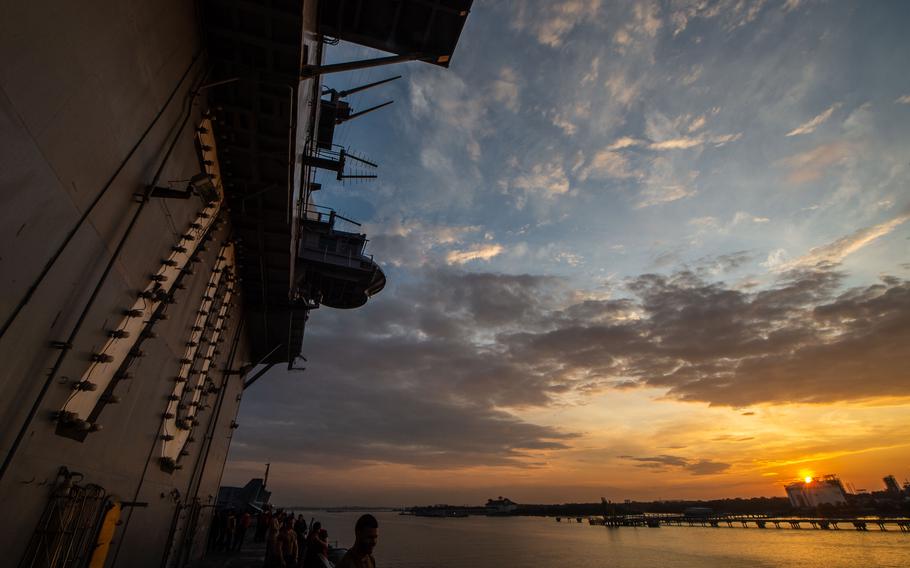 A sunrise lights a boat in a port.